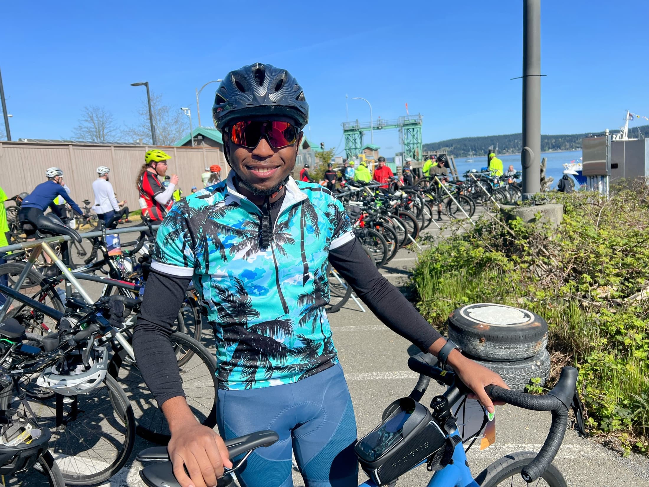 Richard with his bike at a ride start on the Puget Sound waterfront, other riders gathered behind him